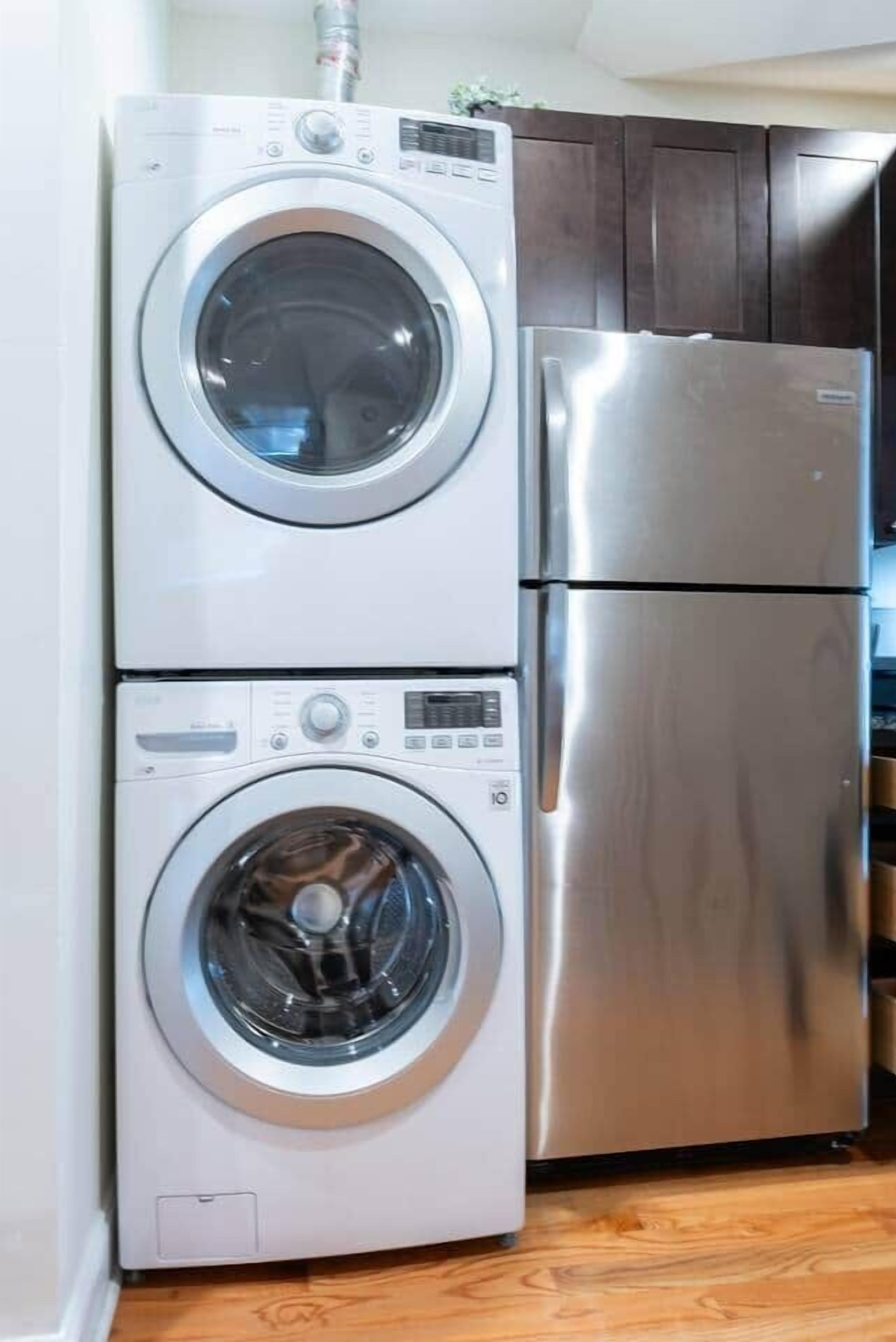 Een compacte keuken met een roestvrijstalen koelkast en een gestapelde wasmachine en droger.