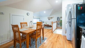 A modern kitchen with a refrigerator, wooden dining table, and chairs.