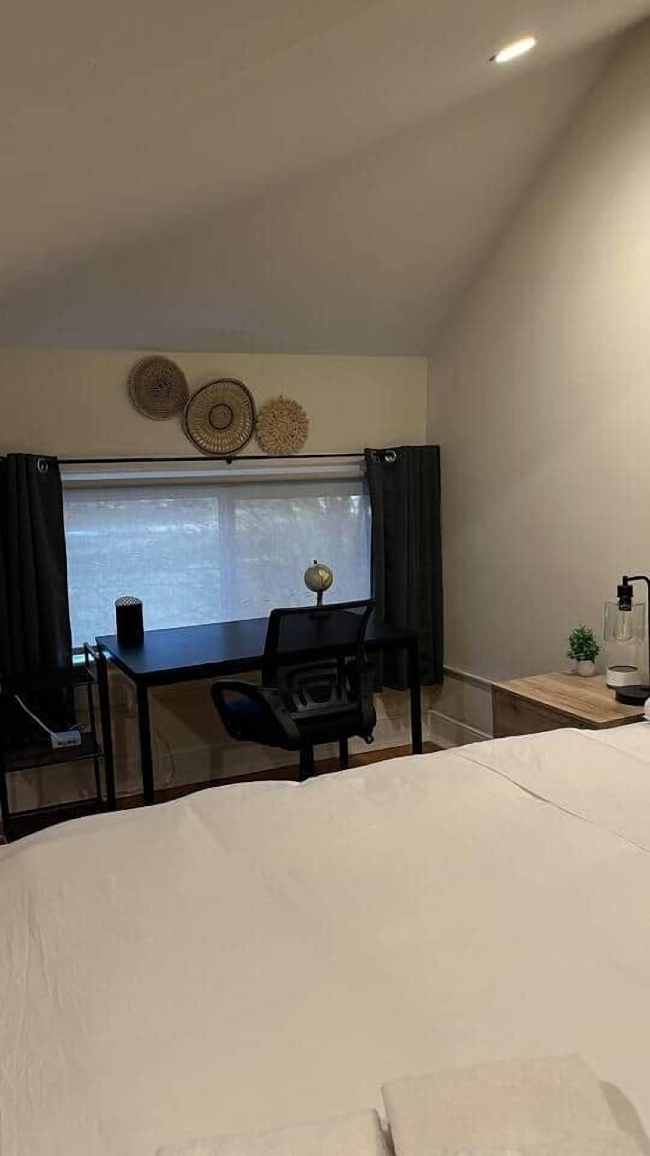 A bedroom with a bed, a desk, a chair, a globe, and a window with curtains.