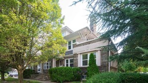 A two-story house with a stone facade, a front porch, and a well-maintained lawn.