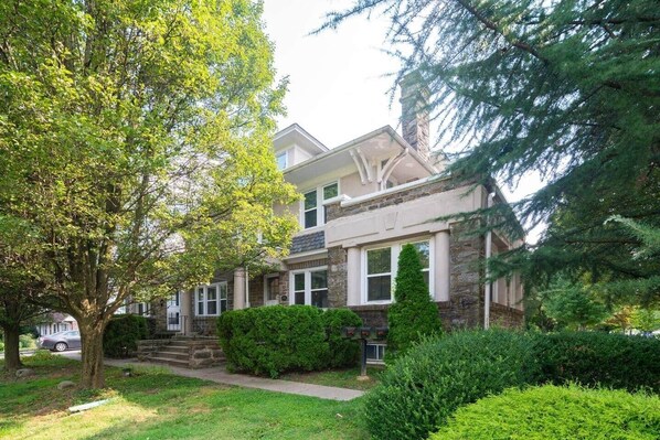 A two-story house with a stone facade, a front porch, and a well-maintained lawn.