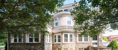 A two-story stone building with a curved corner, multiple windows, and a well-maintained lawn.