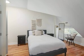 Une chambre à coucher avec un lit, des tables de chevet, une chaise et une fenêtre.