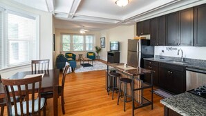 A modern kitchen with dark cabinets, a marble countertop, and a 'Welcome' sign.