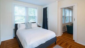 A bedroom with a bed, a ceiling fan, and a view through an open door.