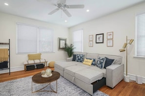 A living room with a sectional sofa, a coffee table, a floor lamp, and a ceiling fan.
