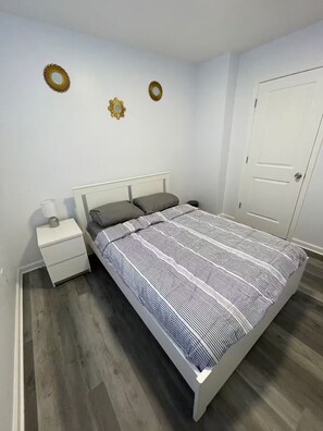 Un dormitorio con cama, mesita de noche y una puerta.