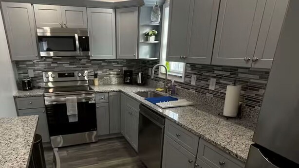 A modern kitchen with grey cabinets, stainless steel appliances, a granite countertop, and a wooden floor. - 2-bedroom apartment in excellent Newburgh with AC and charm (Newburgh)