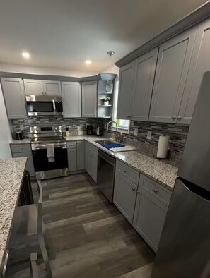A modern kitchen with grey cabinets, stainless steel appliances, a granite countertop, and a wooden floor. - 2-bedroom apartment in excellent Newburgh with AC and charm (Newburgh)