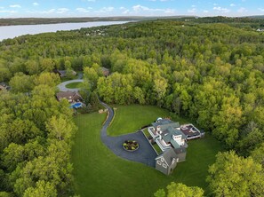 Vue aérienne d’un quartier résidentiel avec des maisons, une piscine et une grande étendue d’eau en arrière-plan.