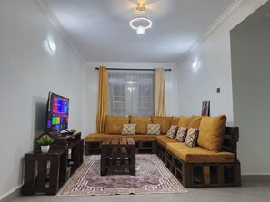 Ein Wohnzimmer mit einer Couch, einem Couchtisch, einem Fernseher und einem Teppich.