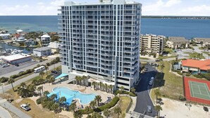 A high-rise hotel with multiple balconies, a swimming pool, and a tennis court. - "Heaven on Top" – 15th-Floor Gulf Views, Pool & Hot Tub , Steps to Beach (Pensacola Beach)
