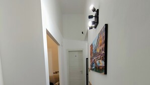 A hallway with a tiled floor, a door at the end, and a wall-mounted light fixture. - Bosuites Rome (Rome)