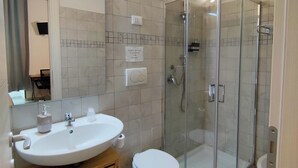 A bathroom with a glass-enclosed shower, a sink with a soap dispenser, and a toilet. - Bosuites Rome (Rome)