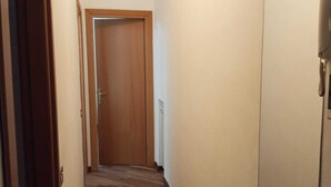 A narrow hallway with wooden flooring and a closed door at the end. - Vibes Pigneto, central location near metro C stop suitable for families (Roma)