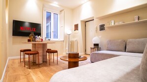 Ein modernes Wohnzimmer mit einem Flachbildfernseher, einem runden Holztisch und einem grauen Sofa.