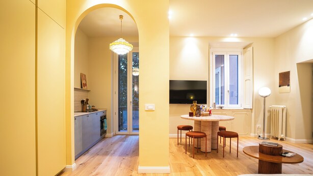 Eine moderne Küche mit Essbereich, einem an der Wand montierten Fernseher und einem großen Fenster.