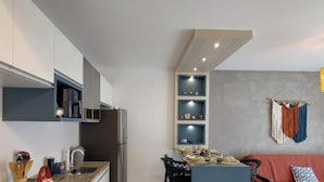 A compact kitchen with a built-in stove, a sink, and a dining area with a table and chairs. - Apartamento Aconchego do Ribeirão - FLN (Florianópolis)
