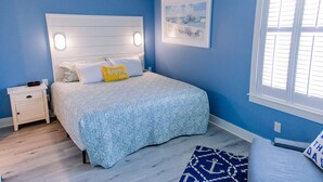 A bedroom with a bed, nightstand, and a window with blinds. - Intracoastal Sanctuary 2BR 2BA in Sabine Pass (Sabine Pass)