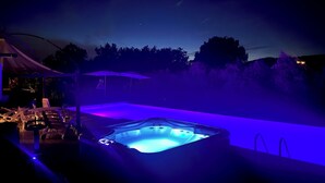 A hot tub with a blue light, surrounded by outdoor furniture and a tent. - Antico Casale San Lorenzo (Toscana)
