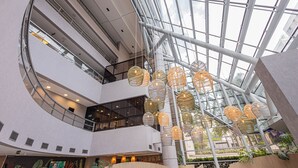 A multi-level atrium with glass ceilings, modern architecture, and hanging light fixtures. - QSP - Jardim Paulista by Anora Spaces (São Paulo)
