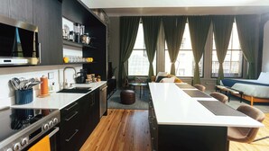 Une cuisine moderne dotée d’un îlot central, un coin repas avec une table et des chaises, et un espace salon confortable avec un canapé et un lit.