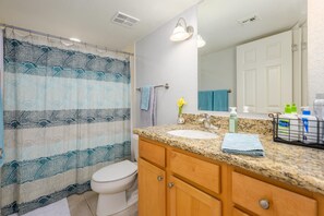 A bathroom with a shower curtain, a toilet, a sink with a granite countertop, wooden cabinets, and a mirror. - CASA MIDDIE-Two Bedroom with the best View (Phoenix, Arizona)