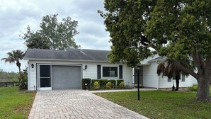 A single-story house with a garage, a paved driveway, and a well-maintained lawn. - Gorgeous 2-bedroom house with AC in charming The Villages (The Villages)