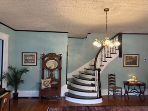 A staircase with a wooden handrail, a chandelier, and a framed picture on the wall. - Cromwell House- A historic, restored 4-bedroom home in beautiful South Frankfort (Frankfort)