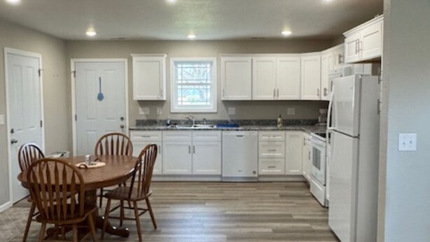 A kitchen with white cabinets, a dining table with chairs, and a refrigerator. - Cozy East Duplex (Seymour)