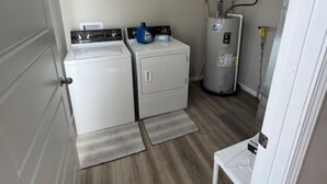 A laundry room with a dryer, washing machine, and water heater. - Cozy East Duplex (Seymour)