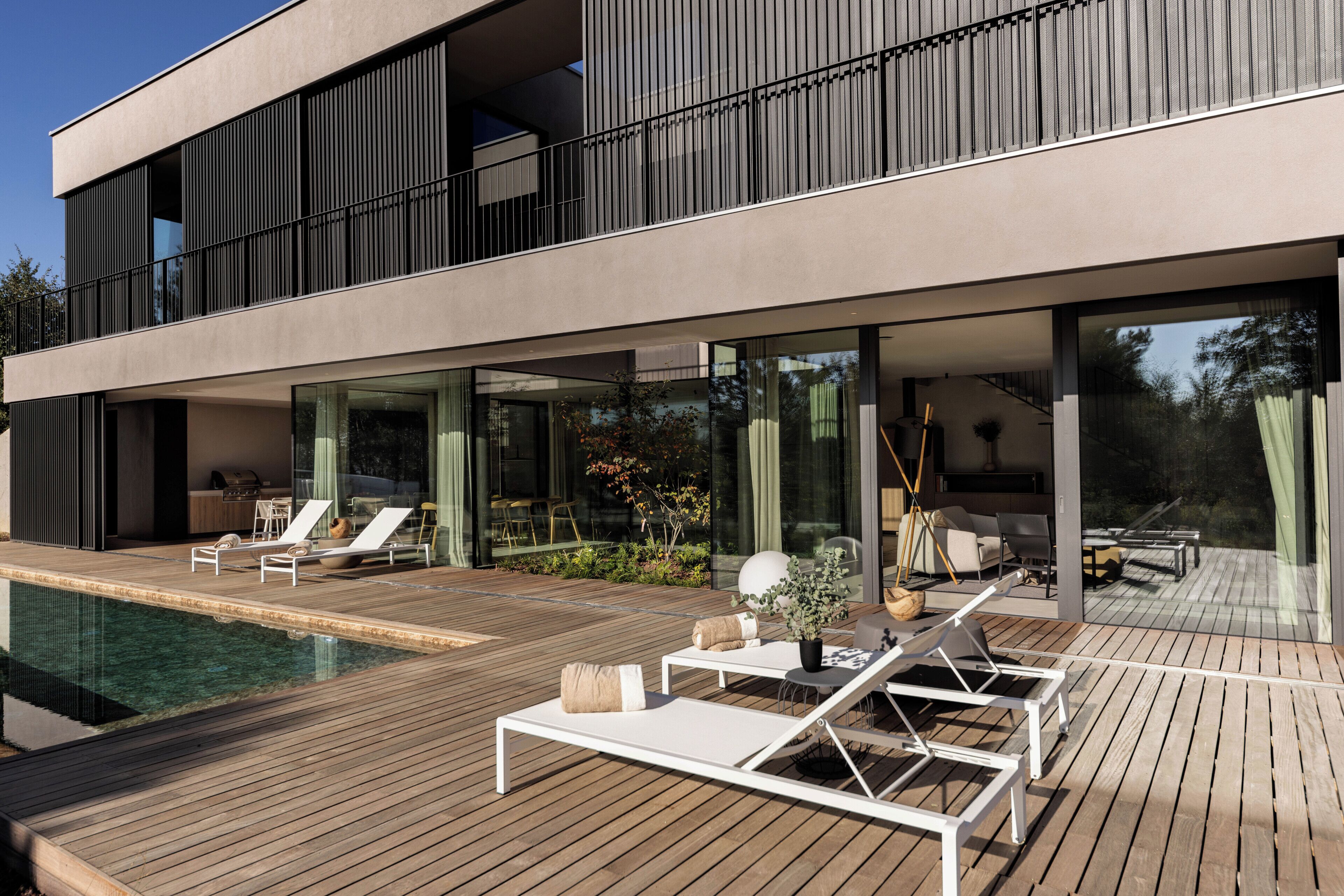 A modern house with a pool, lounge chairs, and a deck.