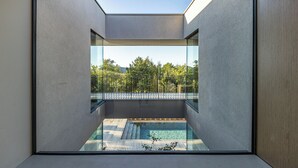 En modern inredning med ett takfönster, en pool och utsikt över grönområden.