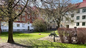 A park with a picnic table, a swing, and a tree. - Harbor-View Loft | 2BR Near City (Gothenburg)