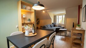 A modern living room with a dark wooden dining table, a sofa, and a small wooden side table. - Harbor-View Loft | 2BR Near City (Gothenburg)