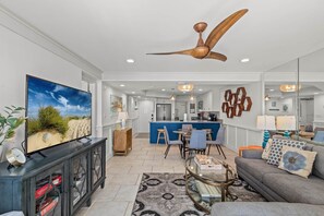 A modern living room with a television, sofa, coffee table, and dining area. - Pinnacle Port, Unit C3-601 (Panama City Beach)