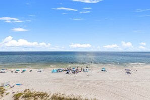 A beach with clear skies, calm water, and people relaxing under umbrellas. - Pinnacle Port, Unit C3-601 (Panama City Beach)