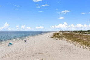 Ein Strand mit einem Zelt, einigen Personen und einem klaren Himmel.