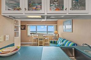 A kitchen with a dining area, a view of the beach, and a sofa. - Pinnacle Port, A-110 (Panama City Beach)