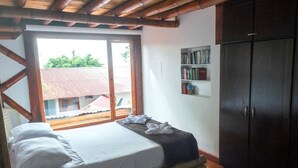 A bedroom with a bed, a bookshelf, and a wardrobe. - Cozy Lodging in the coffee growing region (Ulloa)