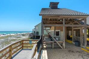 Una casa de playa de madera con balcón con vistas a la playa y al océano.