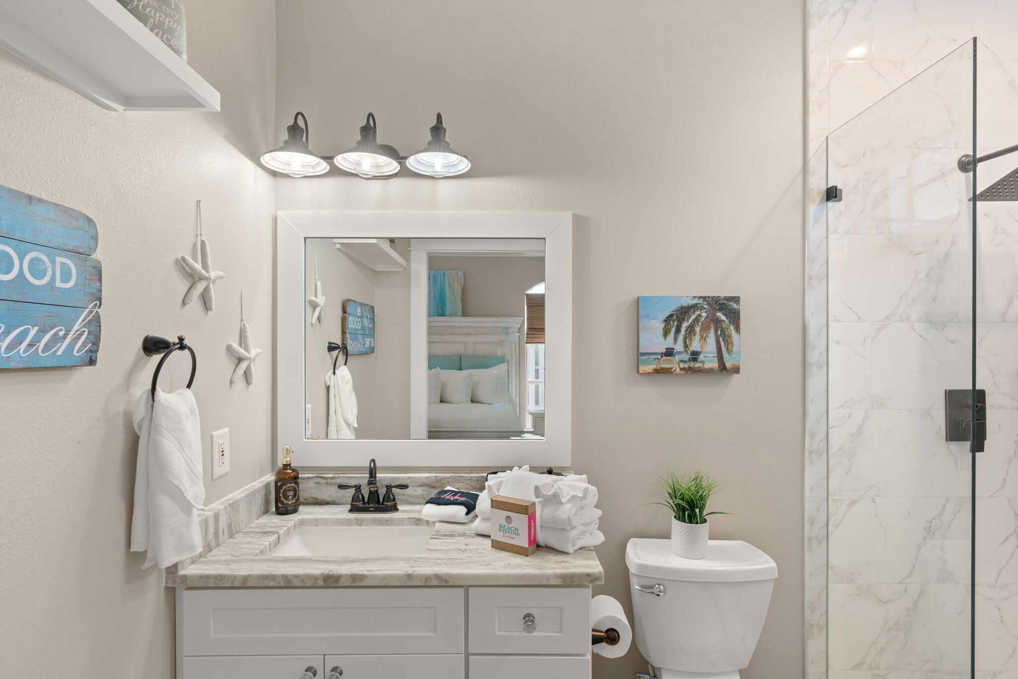 A bathroom with a marble sink, a toilet, a glass shower enclosure, a large mirror, and a towel rack.
