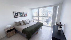 Une chambre à coucher moderne avec une grande fenêtre, un lit, une table de chevet et une plante en pot.