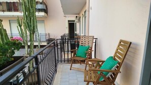 Ein Balkon mit Holzstühlen und einem Blumentopf.
