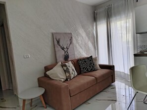 A living room with a brown sofa, a small side table, and a painting of a deer on the wall. - Convent Palace (Barrafranca)