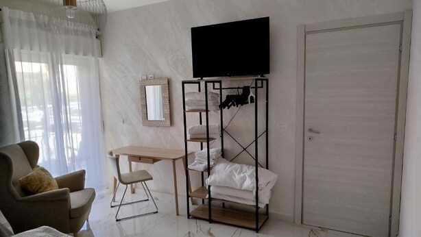 Ein Hotelzimmer mit einem Bett, einem Schreibtisch, einem Stuhl, einem an der Wand montierten Fernseher und einem Kleiderschrank.