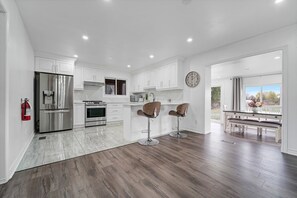 A modern kitchen with white cabinets, stainless steel appliances, and a wooden floor. - Our stylish, comfy home in wine country blends relaxation & convenience. (Niagara-on-the-Lake)