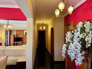 Eine Hotelhalle mit einer Couch, einem Fernseher, einer Treppe und einer Blumenkomposition.