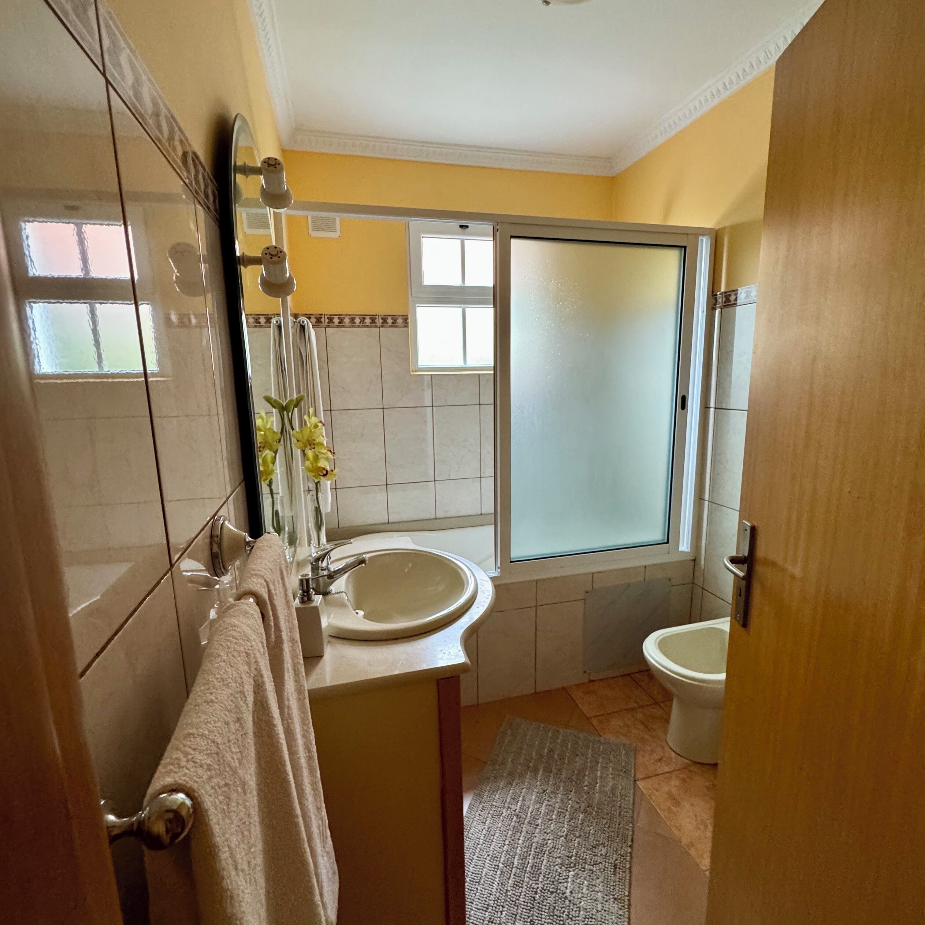 A bathroom with a sink, mirror, towel rack, and a shower area.