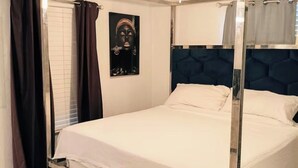 A four-poster bed with a headboard, a ceiling fan, and a wall-mounted light fixture. - 3-bedroom house in amazing Orlando with AC and fitness room-BEACH STYLE BUNGALOW (Orlando)